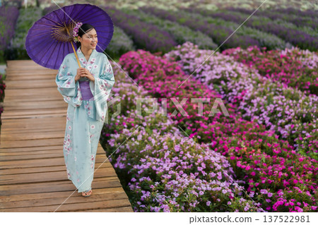 woman in yukata (kimono dress) holding umbrella with flower blooming in garden 137522981