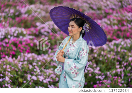woman in yukata (kimono dress) holding umbrella with flower blooming in garden 137522984
