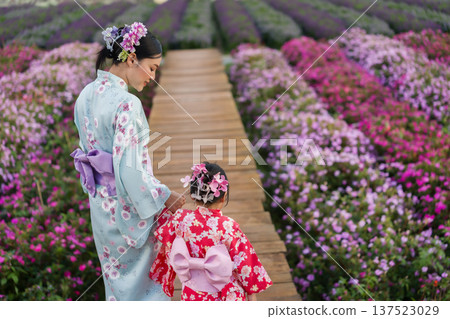 woman and child girl in yukata (kimono dress) walking together with flower blooming in garden woman and child girl in yukata (kimono dress) walking together with flower blooming in garden 137523029