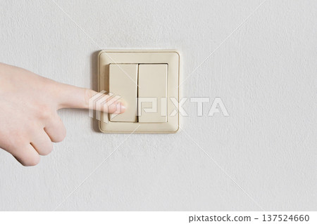 Hand pressing light switch on textured cream wall Hand pressing light switch on textured cream wall 137524660