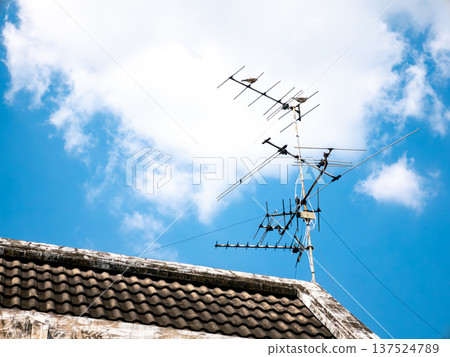 Old TV Antenna on Roof with Blue Sky and White Clouds Background Old TV Antenna on Roof with Blue Sky and White Clouds Background 137524789