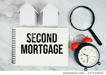 Second Mortgage text written on notepad with house model, magnifying glass and alarm clock on marble background 137524843