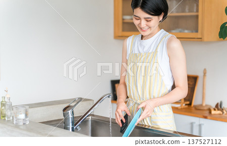 一名婦女/家庭主婦穿著圍裙洗碗 一名婦女/家庭主婦穿著圍裙洗碗 137527112
