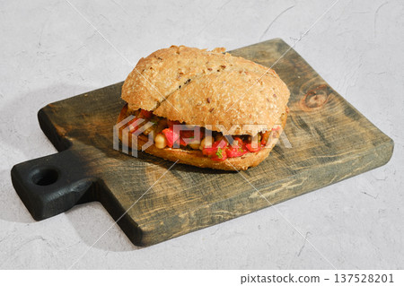 Roasted eggplant chickpeas and bell pepper sandwich on a wooden cutting board in a kitchen setting 137528201