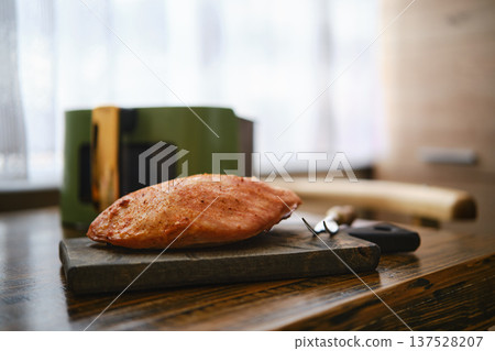 Roasted pork fillet rests on a wooden cutting board in a kitchen 137528207