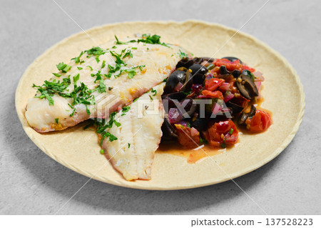 Fish served with a vegetable mix on a plate in a kitchen setting for a meal preparation 137528223
