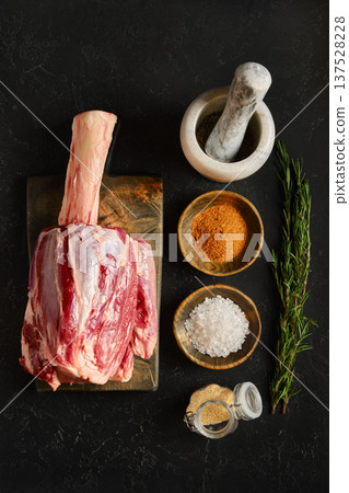 Raw meat prepared for cooking with spices and herbs on wooden board in kitchen setting 137528228