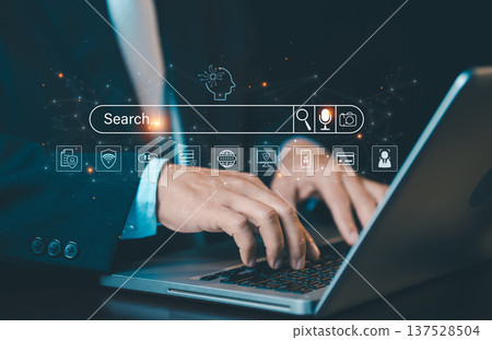 Hands typing on laptop with digital search bar and AI icons. Concept of SEO, information searching, artificial intelligence discovery, and data browsing. Hands typing on laptop with digital search bar and AI icons. Concept of SEO, information searching, artificial intelligence discovery, and data browsing. 137528504