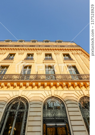 Haussmann style building facade in Paris, France, showing elaborate architecture, ornate balconies, decorative elements under a clear blue sky 137528929