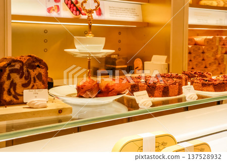 Paris bakery display showcasing fresh cakes, madeleines, and tarts, tempting sweet treats for customers 137528932