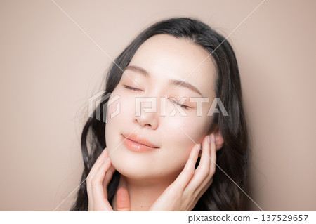 Beauty image of a young woman with beautiful black hair and a beige background. Image of skin care and other skin concerns. 137529657