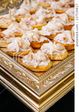 Appetizers with chicken in a French baguette on a tray with a golden pattern Appetizers with chicken in a French baguette on a tray with a golden pattern 137530617