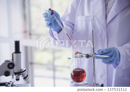 Close up Scientist woman holding chemical test glass tube testing science laboratory. Crop Lab technician holding red drop to glass tube blood sample. Scientist Woman working test medical chemistry Close up Scientist woman holding chemical test glass tube testing science laboratory. Crop Lab technician holding red drop to glass tube blood sample. Scientist Woman working test medical chemistry 137531512