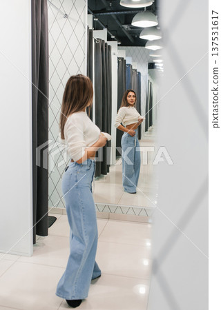 Young Woman Adjusting Jeans In Store Mirror 137531617