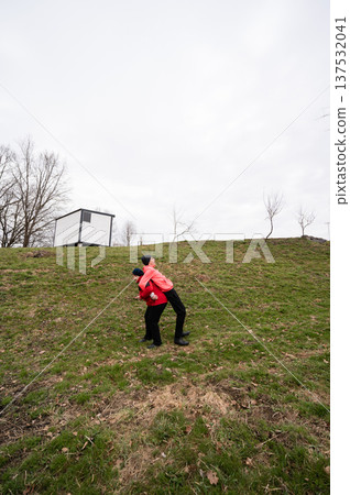 Couple joyfully embraces on a grassy hillside under a cloudy sky during early spring in a tranquil outdoor park 137532041