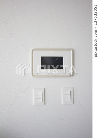It's a white wall with an intercom and a switch. 137532053