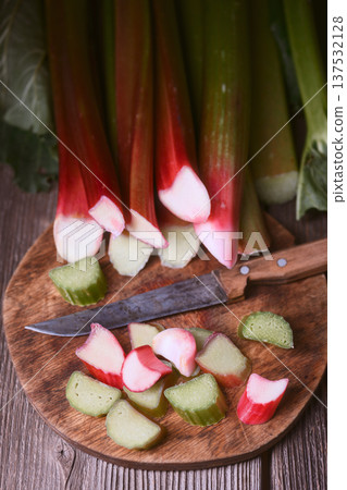 Fresh rhubarb stems and cut pieces on round chopping board 137532128