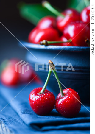 Pair of ripe cherries on blue napkin with ceramic bowl Pair of ripe cherries on blue napkin with ceramic bowl 137532163