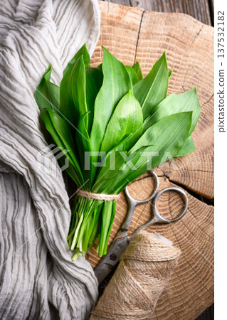 Wild garlic bundle arranged on cutting board with scissors Wild garlic bundle arranged on cutting board with scissors 137532182