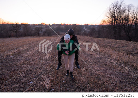 Embracing the joyful companionship of friends as the sun sets, we delight in a carefree moment together on a picturesque field during the enchanting golden hour 137532255
