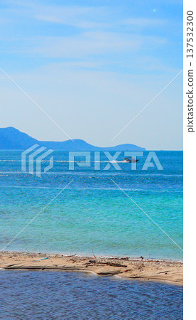 Bright blue sea with white sand beach on sunny day. Speed boat at Mountains distant on blue sky. Bright blue sea with white sand beach on sunny day. Speed boat at Mountains distant on blue sky. 137532300