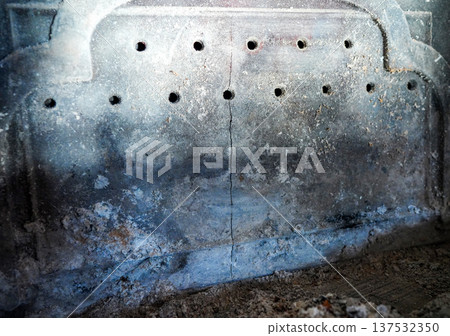 Crack in the wall of a cast-iron stove. Crack in the metal of a heating stove due to improper use.  137532350