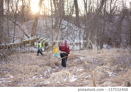 Community members engage in outdoor restoration efforts in a winter landscape, clearing brush and fostering growth as the sun rises in a serene woodland area Community members engage in outdoor restoration efforts in a winter landscape, clearing brush and fostering growth as the sun rises in a serene woodland area 137532408