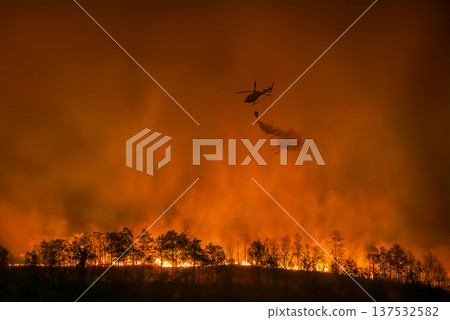 Fire fighting helicopter carry watethar bucket to extinguish the forest fire. Fire fighting helicopter carry watethar bucket to extinguish the forest fire. 137532582