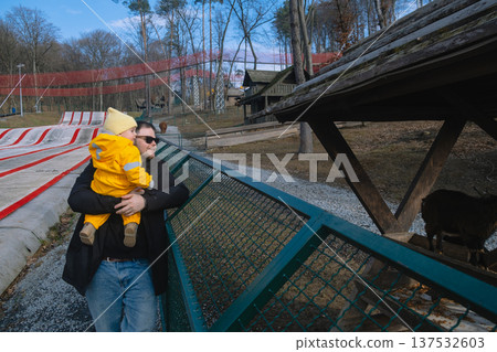 Father holding toddler at petting zoo enclosure 137532603