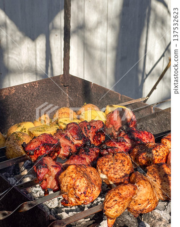 Skewered meat and potatoes grilling over charcoal outdoors Skewered meat and potatoes grilling over charcoal outdoors 137532623