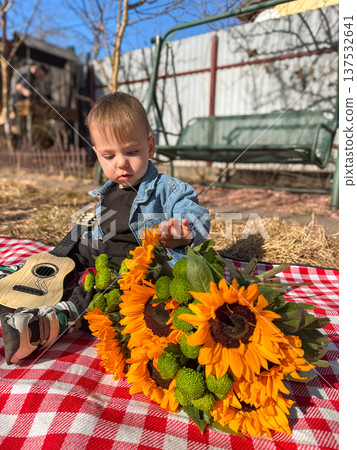 Toddler with ukulele and sunflower bouquet on picnic blanket Toddler with ukulele and sunflower bouquet on picnic blanket 137532641