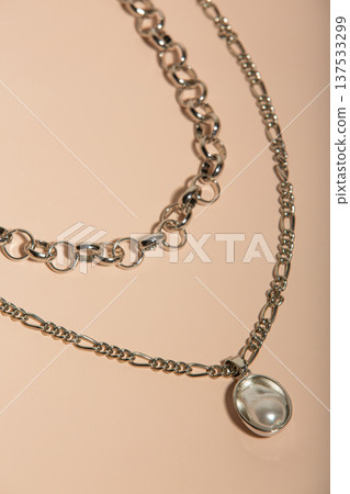 Sophisticated Silver Chain Adornment With Smooth Oval Pearl Resting On Warm Peach Background Sophisticated Silver Chain Adornment With Smooth Oval Pearl Resting On Warm Peach Background 137533299