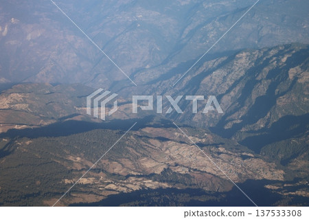 Green trees mountain range landscape seen from airplane window on mountain flight 137533308