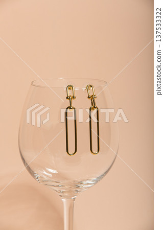 Elegant Gold Earrings. Delicate And Stylish Gold Earrings Set Against Gentle Peach Hue For Magazine Shots Elegant Gold Earrings. Delicate And Stylish Gold Earrings Set Against Gentle Peach Hue For Magazine Shots 137533322