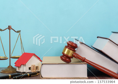 Legal Background with Scales and House Model. A lawyer's desk featuring law books and a gavel. 137533964