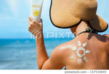 Skin care. Sun protection. Woman apply sun cream. Woman With Suntan Lotion On Beach In Form Of The Sun. Portrait Of Female With Drawn Sun On A Shoulder. Suncream. Girl Holding Moisturizing Sunblock Skin care. Sun protection. Woman apply sun cream. Woman With Suntan Lotion On Beach In Form Of The Sun. Portrait Of Female With Drawn Sun On A Shoulder. Suncream. Girl Holding Moisturizing Sunblock 137534045