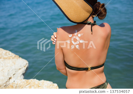 Woman enjoying sunny beach vacation with sunscreen lotion and decorative suncream sun Woman enjoying sunny beach vacation with sunscreen lotion and decorative suncream sun 137534057