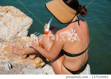 Beautiful woman relaxing on Mediterranean beach with sunscreen lotion Beautiful woman relaxing on Mediterranean beach with sunscreen lotion 137534062