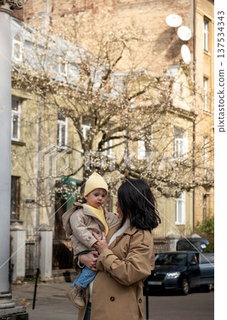 Mother holding toddler on city street in spring Mother holding toddler on city street in spring 137534343