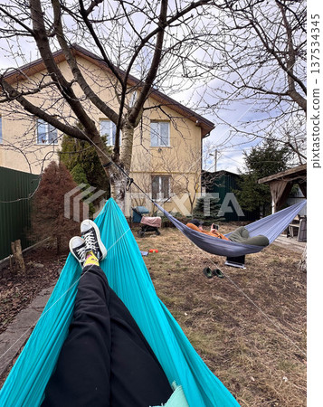 Relaxing in a backyard hammock with suburban house view 137534345