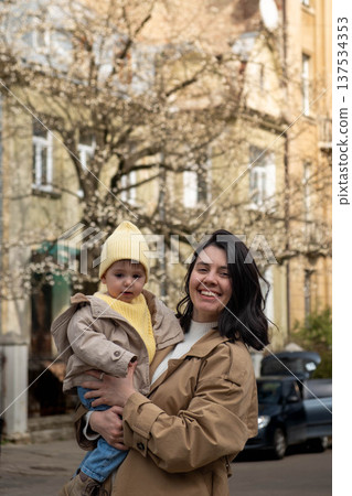 Mother holding toddler on city street in spring Mother holding toddler on city street in spring 137534353