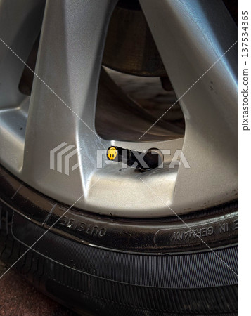 Car wheel close-up with tire valve stem and pressure cap 137534365
