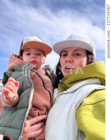 Mother holding toddler outdoors under blue sky 137534367