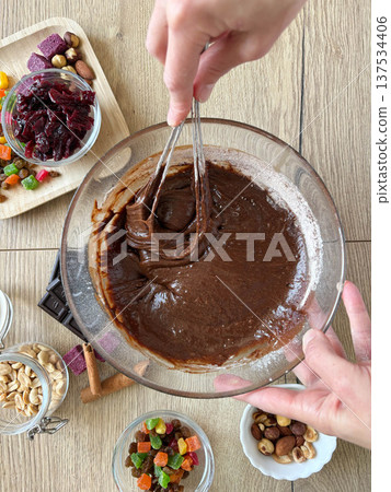Women's hands whisking chocolate dough in a glass bowl. Baking, structure and consistency. Top view. Women's hands whisking chocolate dough in a glass bowl. Baking, structure and consistency. Top view. 137534406