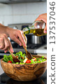 Pouring Olive Oil Over Fresh Green Salad 137537046