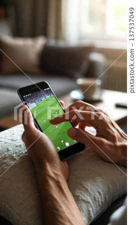 Hands Using Smartphone to Watch Soccer at Home Hands Using Smartphone to Watch Soccer at Home 137537049