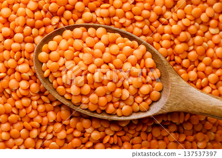 Red lentils in a wooden plate background. Top view 137537397