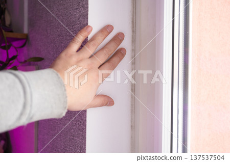 Caucasian hand on moldy window frame highlighting household mold problem 137537504