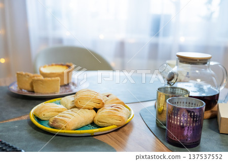 Assorted pastries and tea on table in cozy kitchen setting 137537552
