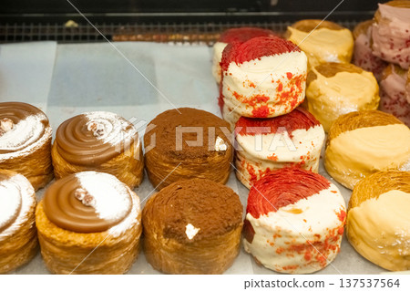 Assorted pastries with cream and chocolate toppings on display 137537564